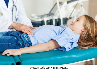 Unrecognizable doctor palpating belly of little girl lying on couch in doctors office and smiling - Shutterstock ID 1868908261