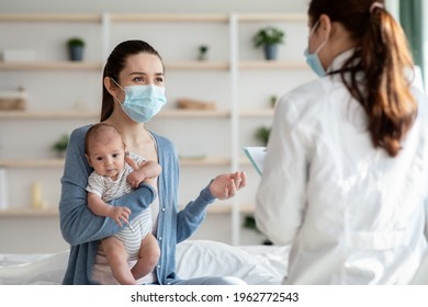 Unrecognizable Doctor In Protective Medical Mask Visiting Mother With Newborn Baby At Home, Millennial Mom And Her Infant Baby Getting Treatment During Coronavirus Pandemic, Selective Focus