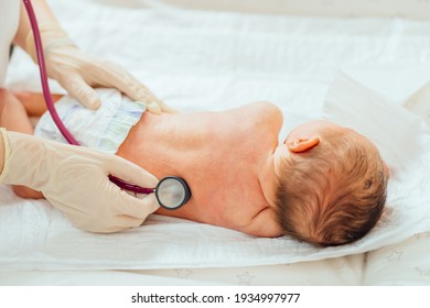 Unrecognizable Doctor With Stethoscope Listens To Heartbeat. Unrecognizable Female Doctor In Medical Gloves Using Hands Examining Little Cute Baby Infant In Clinic. Baby Health Care Concept.