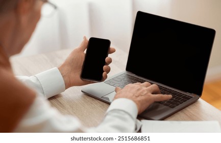 Unrecognizable Elderly Gentleman Using Smartphone And Laptop With Blank Screen Sitting In Office. Mockup, Selective Focus - Powered by Shutterstock