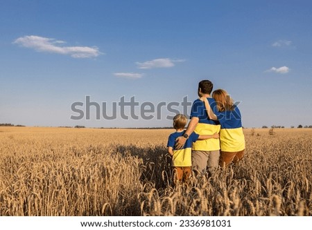 unrecognizable family in same yellow and blue t-shirts stands among ears of corn in wheat field. Stop the war. Pride, support, faith in victory. Independence Day of Ukraine. value of grain for mankind