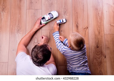 Unrecognizable father with his son playing with cars