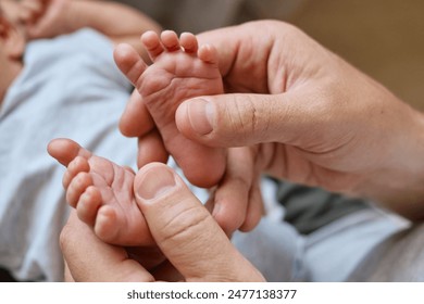 Unrecognizable father making baby massage dad massaging infant bare foot preventive massage for newborn stroking the baby's feet with both hands - Powered by Shutterstock