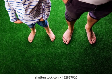 Unrecognizable father and son standing, against artificial green