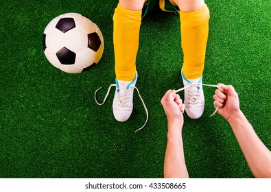 Unrecognizable father tying shoelaces to his son, football - Powered by Shutterstock