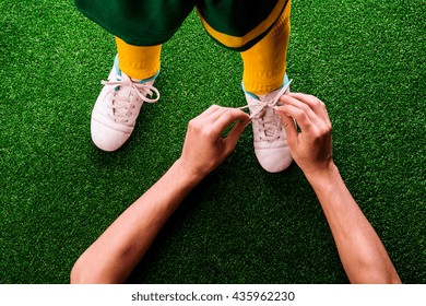 Unrecognizable father tying shoelaces to his son, football - Powered by Shutterstock