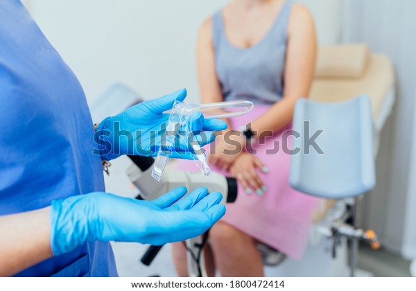 Unrecognizable female doctor gynecologist in\
gloves holding transparent disposable gynecological speculum ready\
for examination, working with\
patient.