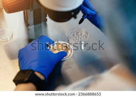 Unrecognizable female embryologist, assisted reproductive technologies, fertilization vet examining sample through microscope in embryology laboratory.