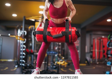 Unrecognizable Female In Sportswear Lifting Heavy Bag While Exercising In Modern Gym