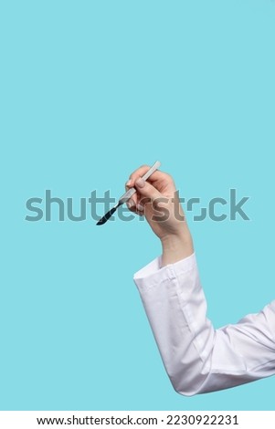 Unrecognizable female surgeon holding metal non-sterile surgical instrument. Doctor shows position of scalpel like writing pen. Tutorial