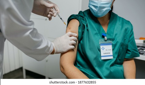 Nicht erkennbare weibliche Chirurgen, die im Büro des Arztes einen Koronavirus-Impfstoff erhalten