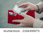 Unrecognizable female takes out 5 euro banknote from a red leather wallet on the street. Payment, salary and banking concept.