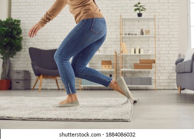 Unrecognizable Female Trips Over Rug. Clumsy Faceless Woman In Uncomfortable Shoes Stumbles On Rug In Living-room And Is About To Fall On Floor. Domestic Accidents And Getting Injured At Home Concept