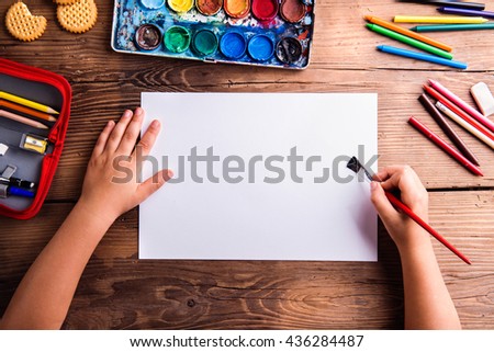 Unrecognizable girl painting on empty sheet of paper