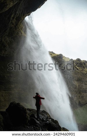 unrecognizable girl standing behind Kvernufoss waterfall. South of Iceland,authentic travel concept