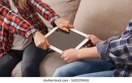 Unrecognizable Greedy Kids Pulling Apart Tablet Computer Not Wanting To Share Sitting On Couch At Home. Siblings Problems. Cropped