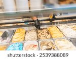 Unrecognizable hands of a worker picking ice cream from counter of a store