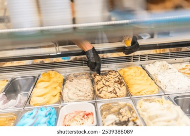 Unrecognizable hands of a worker picking ice cream from counter of a store
