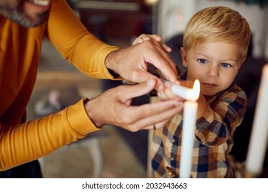 Unrecognizable Jewish Father And His Son Lighting Up Traditional Hanukkah Candles At Home.