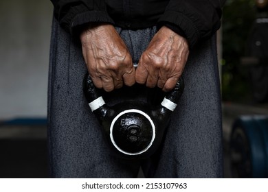 Unrecognizable Latin American Senior Male Holding A Kettlebell With Both Hands During His Rehabilitation And Therapy Workouts At The Gym. Healthy Lifestyle Concept.