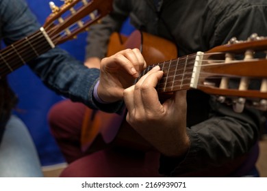 Unrecognizable Latin American teacher corrects and teaches chords on the guitar. Concept music lessons - Powered by Shutterstock