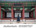 Unrecognizable Latina woman in a black dress and backpack, facing away while admiring the details of a traditional Korean temple in Seoul, South Korea.