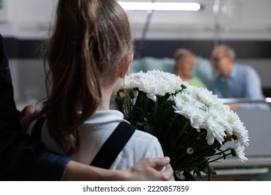 Unrecognizable Little Girl Holding Flowers Bouquet Arriving At Nursing Home, Visiting Sick Grandmother. Toddler Seeing Elderly Lady In Hospital Observation Room With Flower Arrangement As Gift.