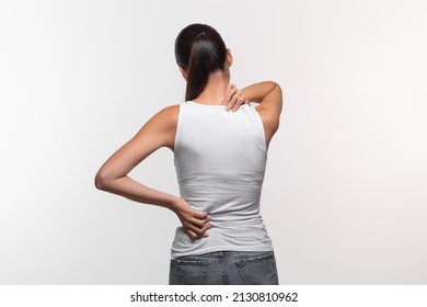 Unrecognizable long-haired brunette woman with neck and back pain rubbing her painful body, lady suffering from office syndrome, back view, white studio background, panorama with copy space - Powered by Shutterstock