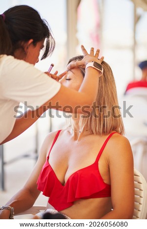 Unrecognizable makeup artist working on a young woman