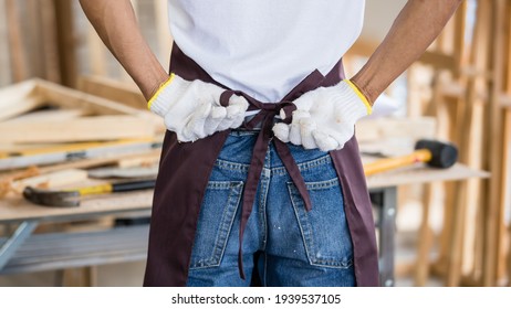 Unrecognizable male carpenter tying apron while preparing to work near workbench in workshop - Powered by Shutterstock