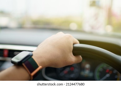 Unrecognizable male driver using left hand grabs on the steering wheel while driving on the road, man driving a car. Beautiful sunlight on the road during man drive a car. Safety driving concept.