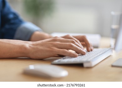 Unrecognizable male employee working on laptop at desk in office, cropped image of young man typing on computer keyboard, writing email or communicating online, side view shot with selective focus - Shutterstock ID 2176793261