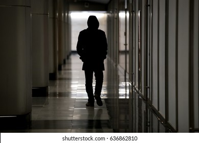 Unrecognizable male figure with hidden face in hood walking in dark hall, looking dangerous, stalking night robber burglar, bad troubled period, hooded guy feeling lost and abandoned, becoming ghost  