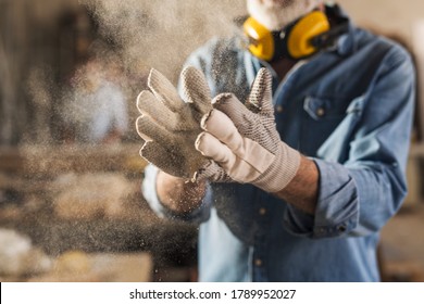 Unrecognizable male hands with work gloves on, clapping to remove sawdust - Powered by Shutterstock