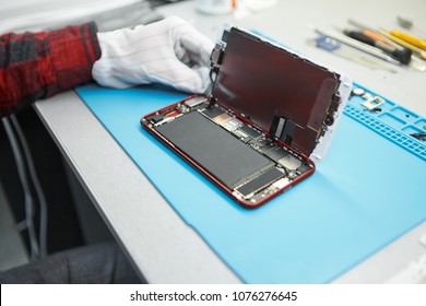 Unrecognizable Male Technician Disassembling Cell Phone At His Workplace, Opening Back Cover To Look Inside And Check Small Parts For Faults. Repair, Maintenance, Computing And Engineering Concept