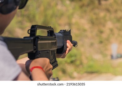 Unrecognizable Man Aiming Shotgun Practicing On Outdoor Firing Range. Blurred Background Horizontal Shot . High Quality Photo