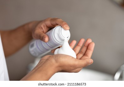 Unrecognizable man applying shave foam on hand, standing in bathroom and preparing for shaving, closeup. Guy making morning beauty routine at home