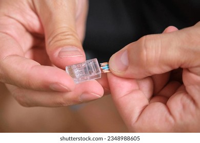 Unrecognizable man attaching net cable to RJ45 connector. - Shutterstock ID 2348988605