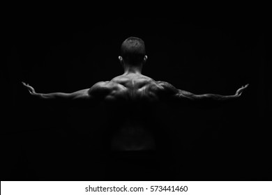 Unrecognizable man bodybuilder shows strong hands and neck muscles, athletic trapezius. Black and white, monochrome studio shot on black background. - Shutterstock ID 573441460