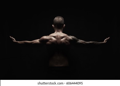 Unrecognizable man bodybuilder shows strong hands and neck muscles, athletic trapezius. Low key, studio shot on black background. - Shutterstock ID 606444095