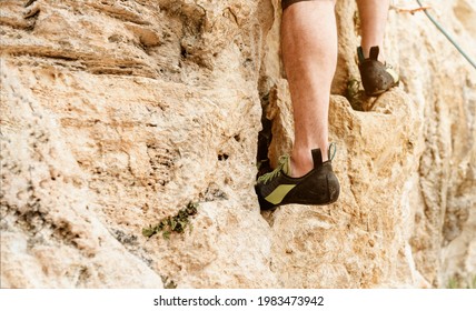 Unrecognizable Man Climbing A Mountain. Rock Climbing Shoes Detail. Risk Sports And Adventure. Mountain Activities.