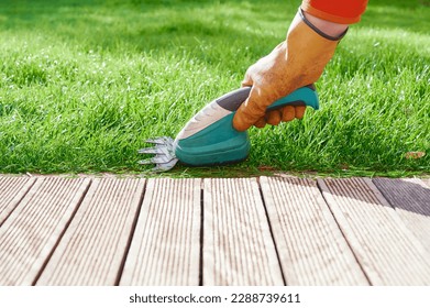 Unrecognizable man cuts grass of the garden edges using a lawn mower scissors. Battery powered gardening tools. - Powered by Shutterstock