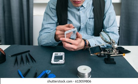 Unrecognizable Man Disassembling Smartphone Free Space. Fixing Process In Repair Shop - Repairman Working With Broken Mobile Phone, Special Tools On Workplace