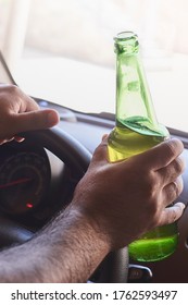 An unrecognizable man drinking beer while driving car. Concepts of driving under the influence, drunk driving or impaired driving