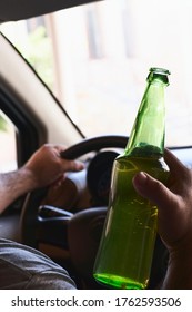 An unrecognizable man drinking beer while driving car. Concepts of driving under the influence, drunk driving or impaired driving