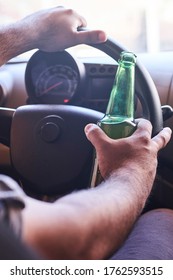 An unrecognizable man drinking beer while driving car. Concepts of driving under the influence, drunk driving or impaired driving
