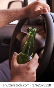 An unrecognizable man drinking beer while driving car. Concepts of driving under the influence, drunk driving or impaired driving