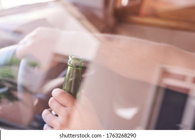 An unrecognizable man drinking beer while driving car. Concepts of driving under the influence, drunk driving or impaired driving