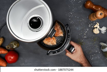 Unrecognizable man hand cooking skinless chicken breast with spices in an air fryer