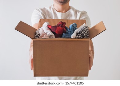 Unrecognizable Man Holding A Cardboard Box Full Of Clothes Close-up. Clothing Donation.